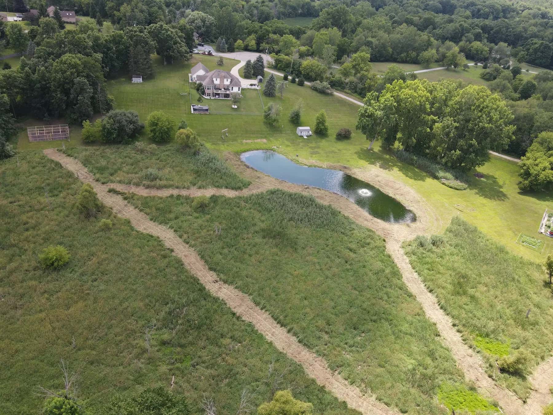Aerial view of mulched walking paths around a pond on wooded acreage