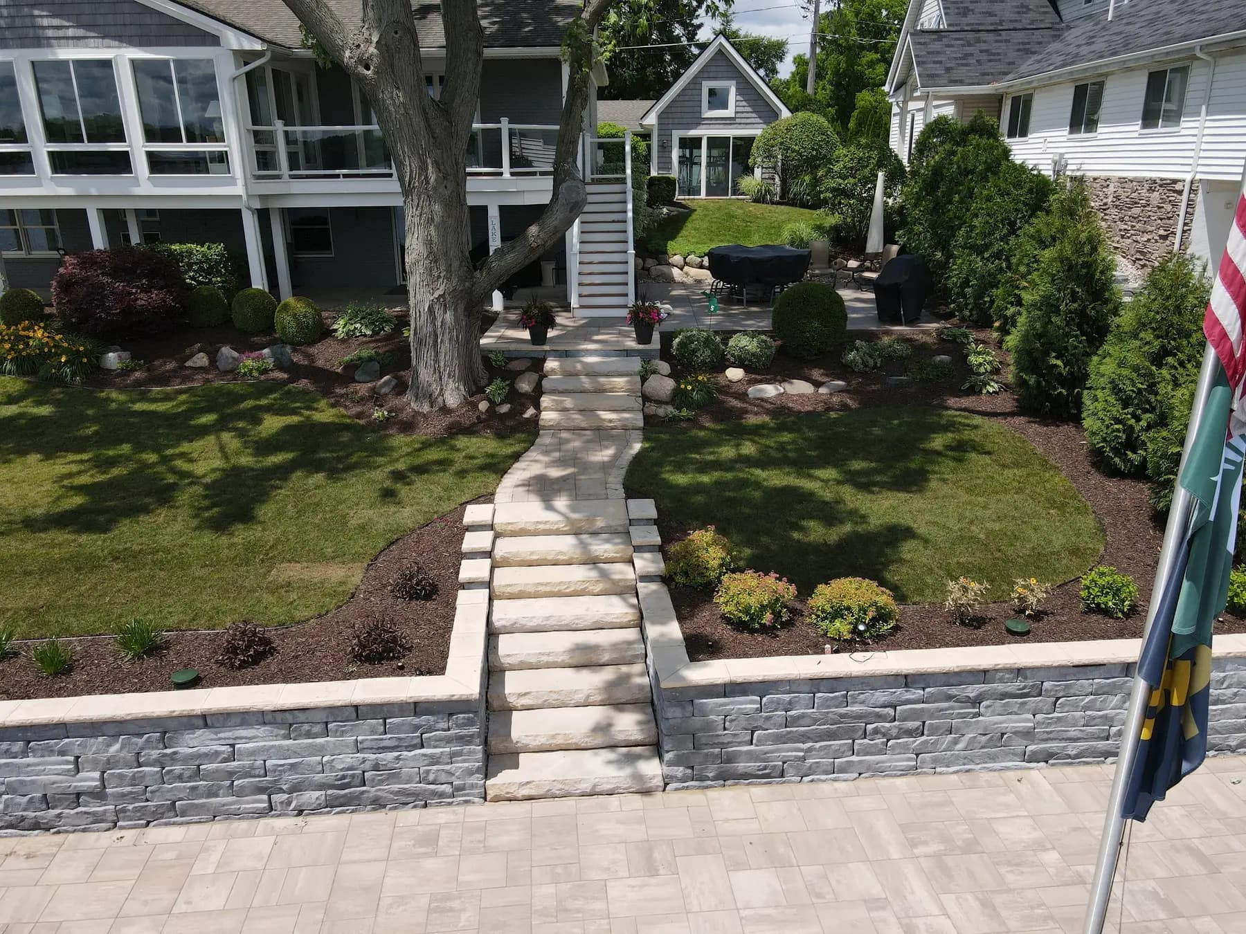 Block retaining wall with stone steps holding a sloped lakefront yard