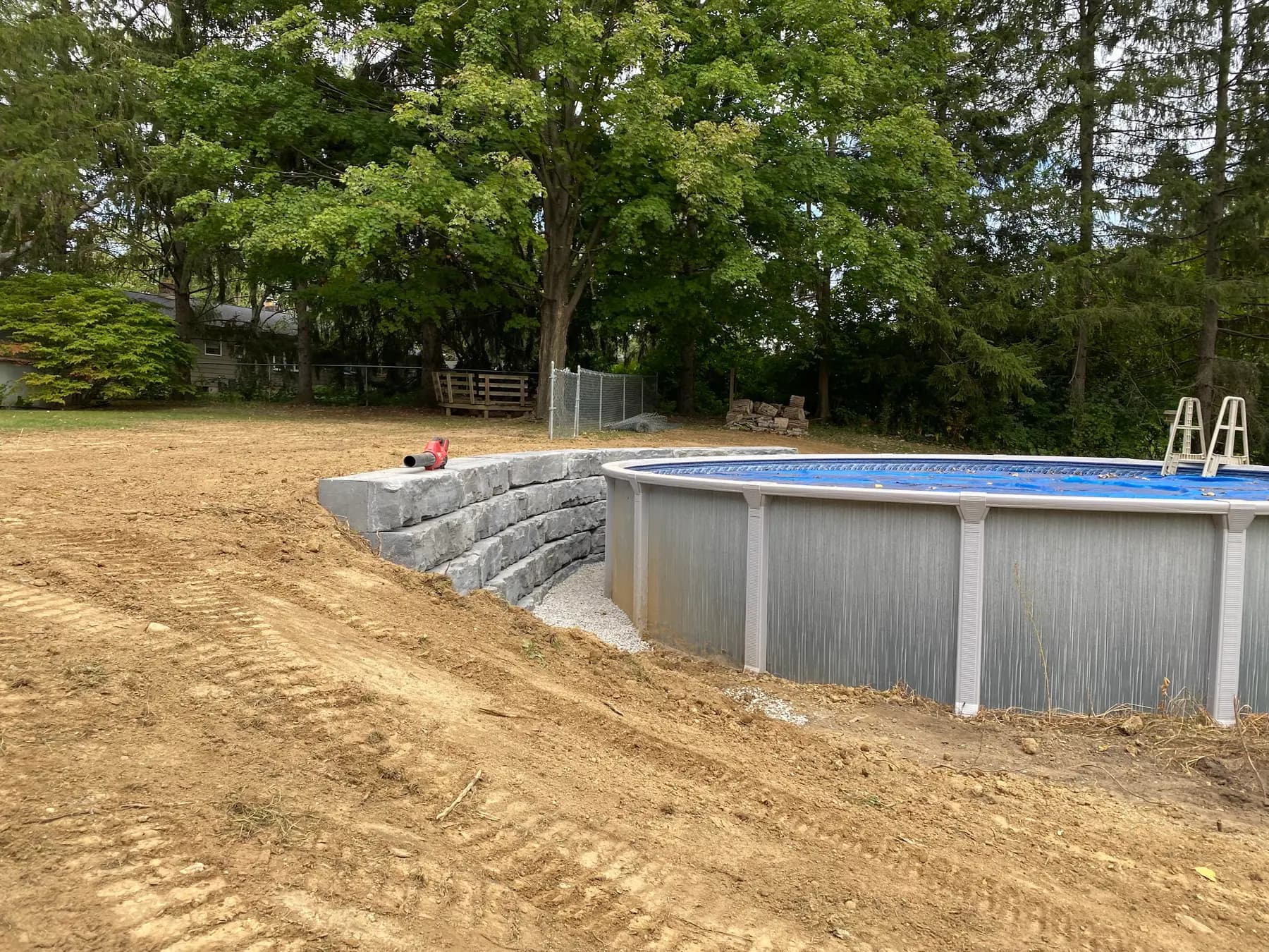 Retaining wall holding a graded slope beside an above-ground pool